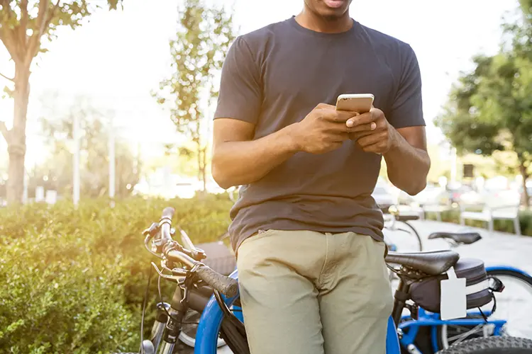A man sitting on a bicycle using a smartphone in a park.